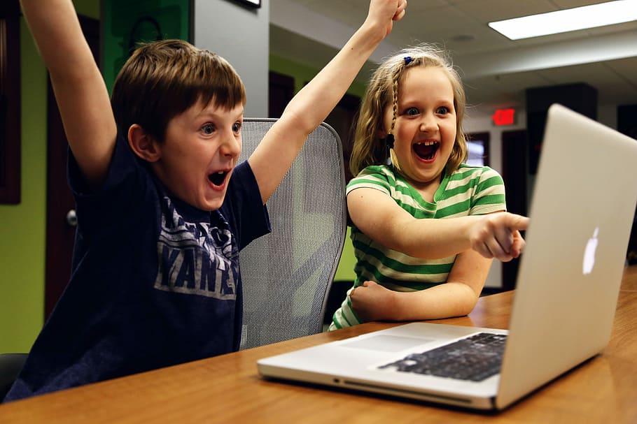 Boy and Girl getting excited by looking at the grey macbook screen