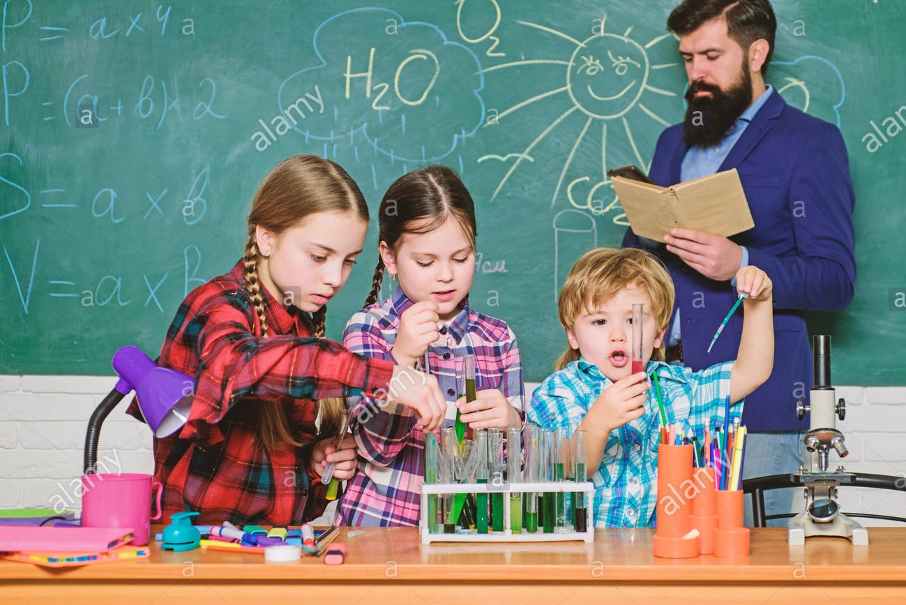 Kids performing chemical activities under teacher's supervision