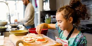 A kid adding toppings to pizza