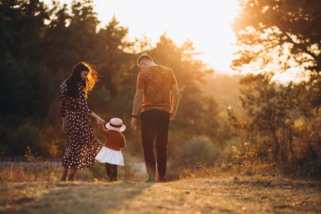 Family with their little daughter helping her to walk