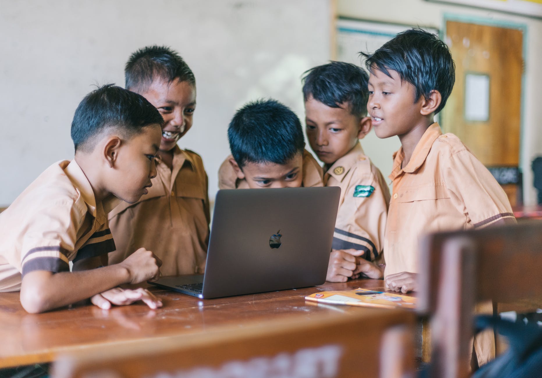 Kids smiling by looking at grey macbook